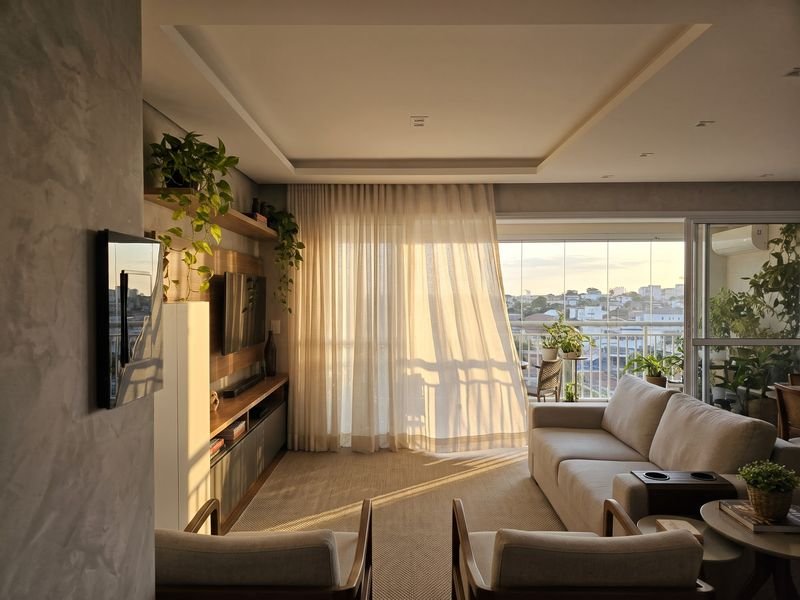 Sala com cortina clara aberta ao fim de tarde
