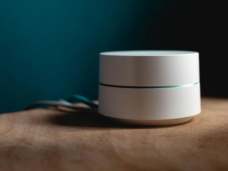 Roteador mesh branco e discreto sobre um móvel de madeira
